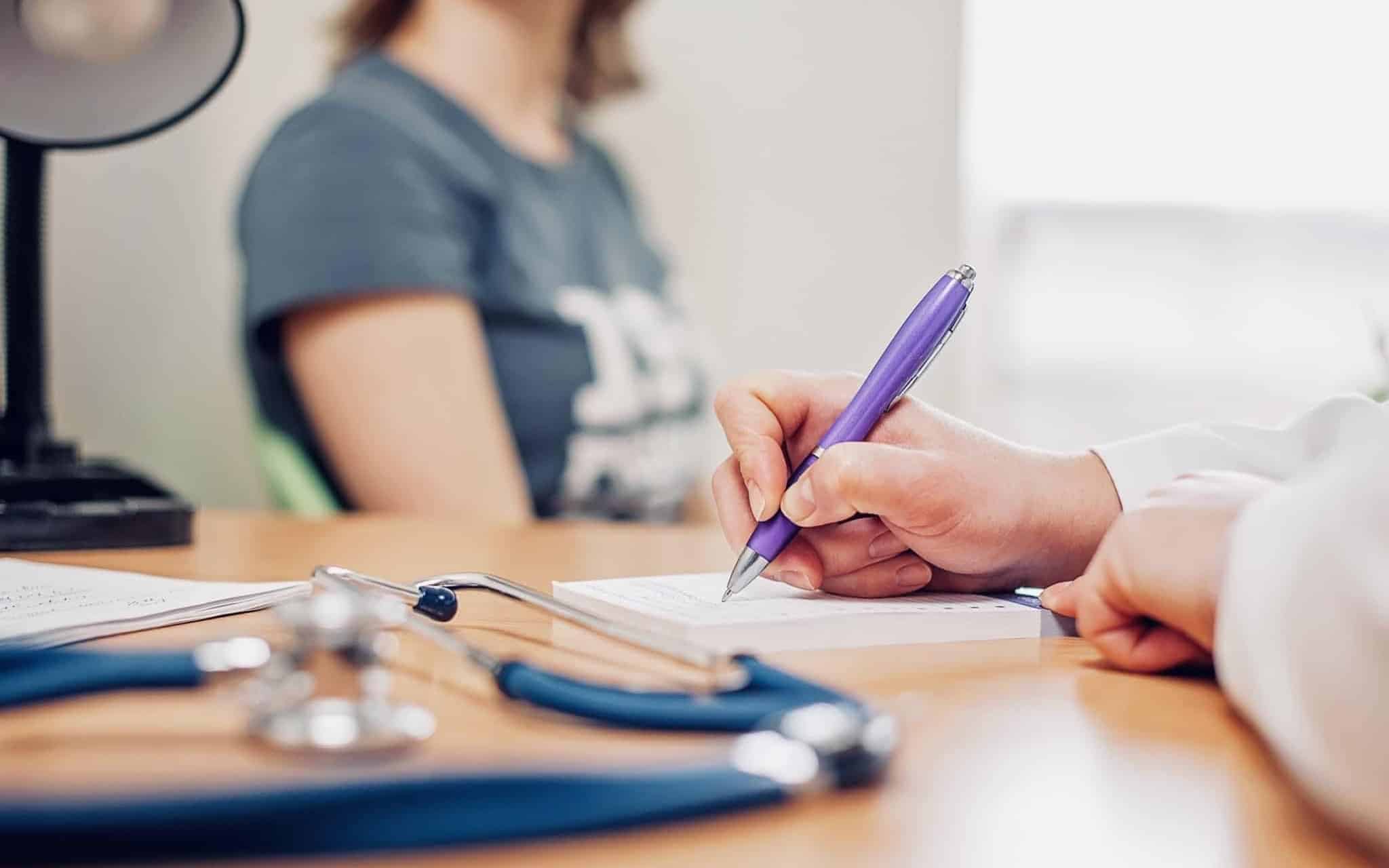 young woman in medical consultation waits for the prescription that the doctor is writing