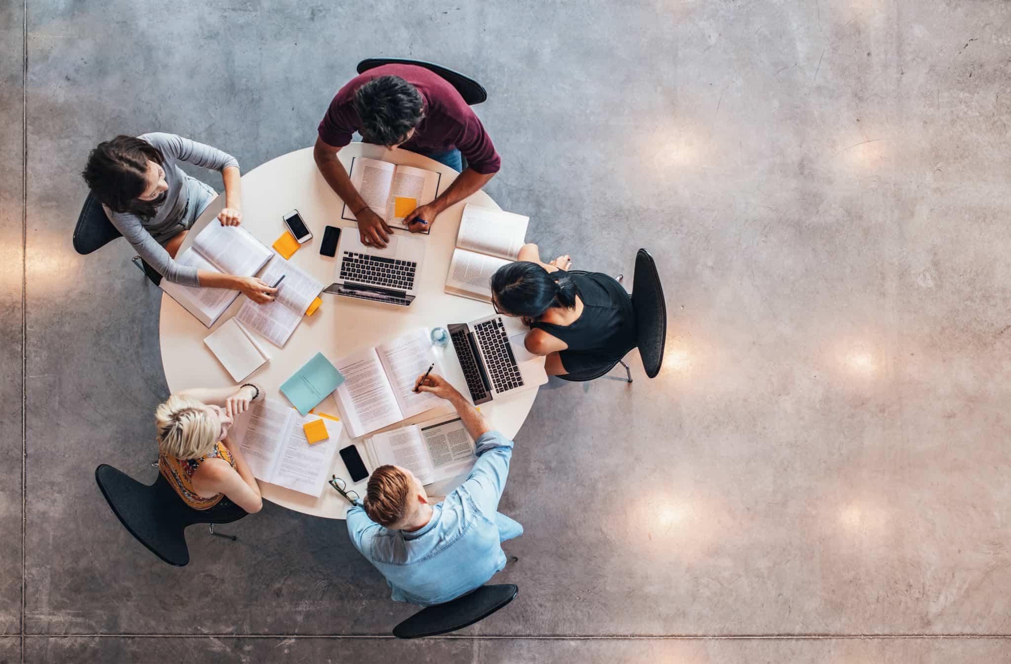 A round table of students with computers seen from above