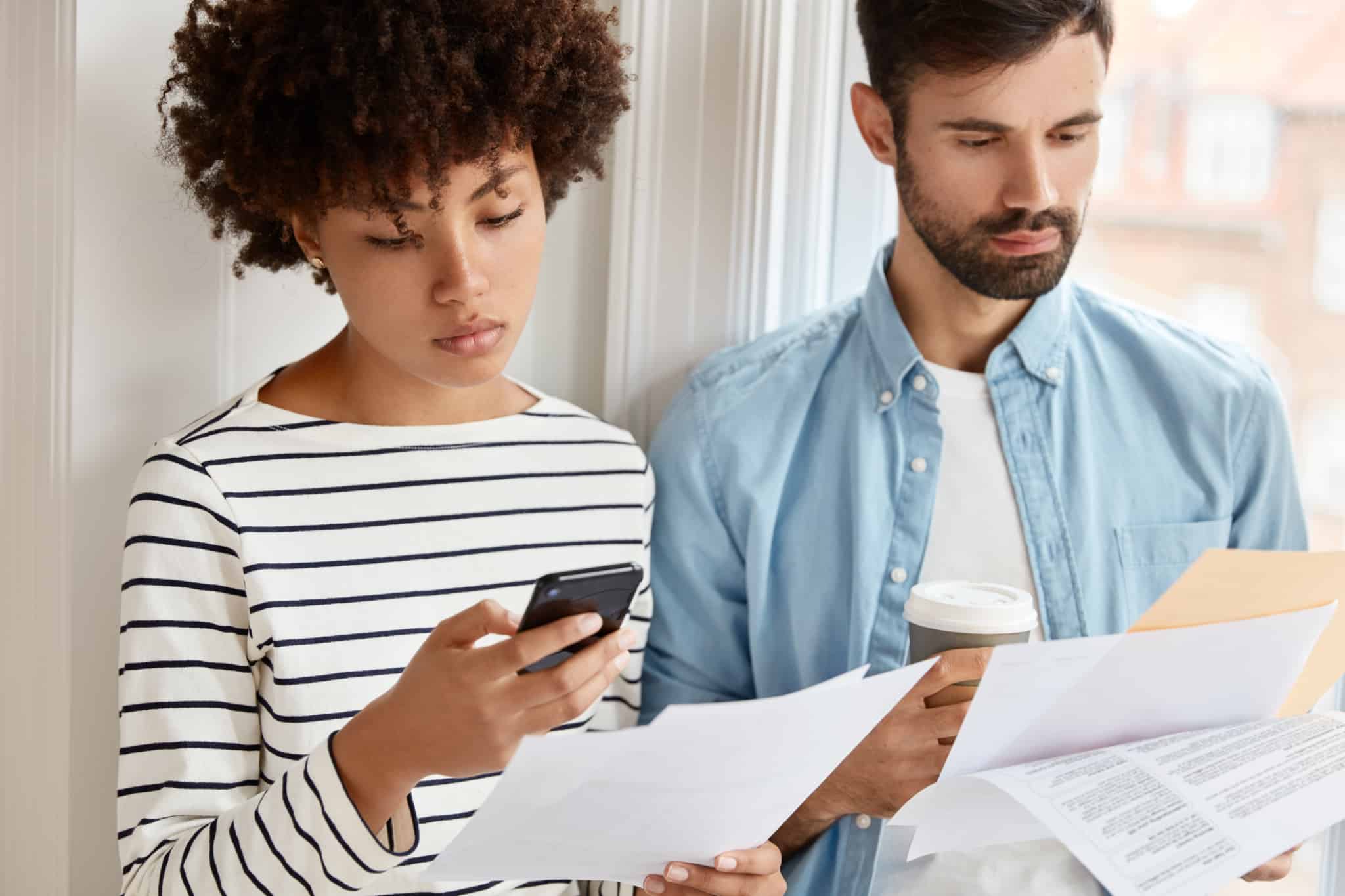 young couple studying documents and doing math to decide how to invest the IRS refund