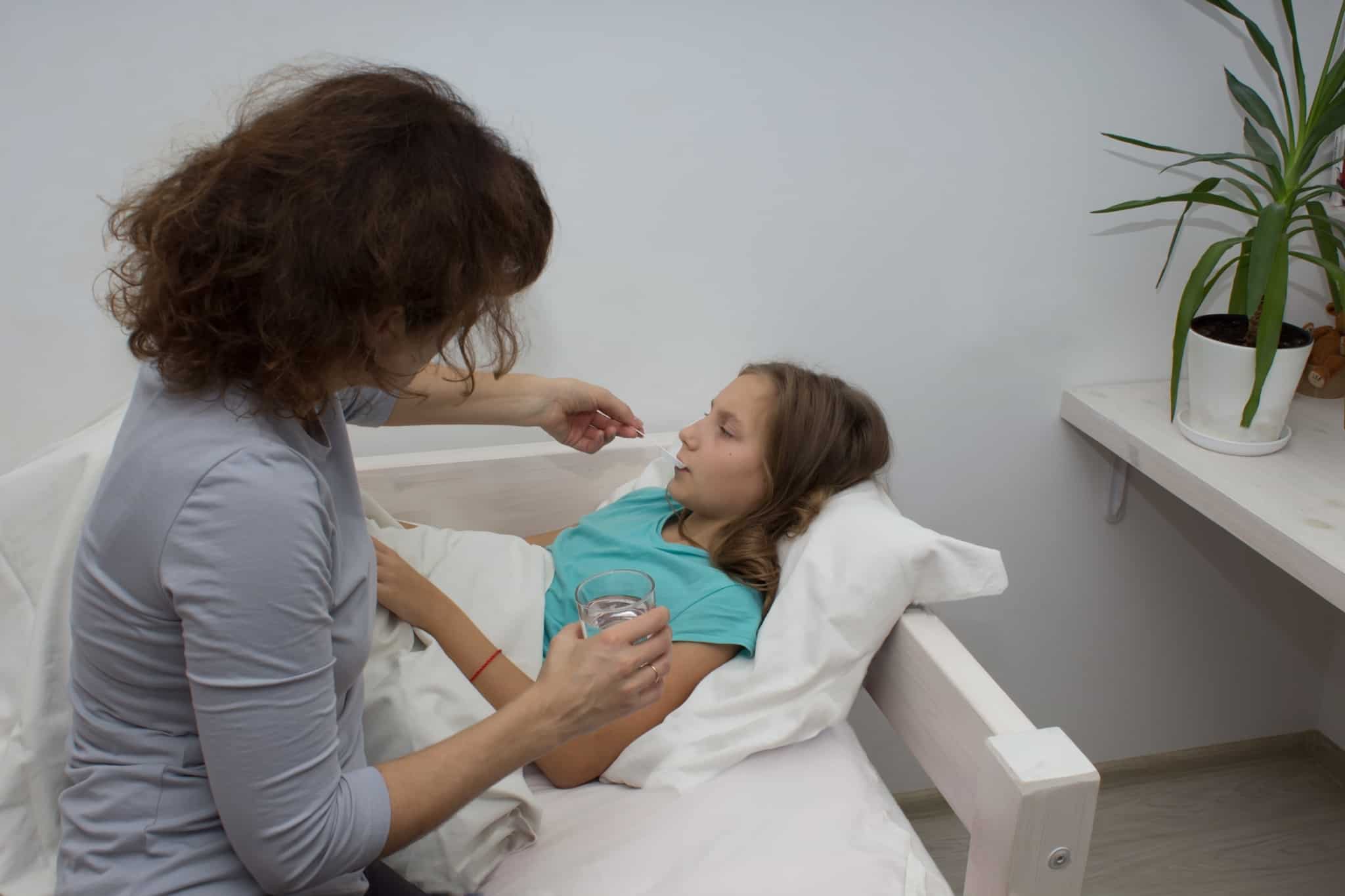 young mother sitting by her youngest daughter's bed provides assistance enjoying low family support